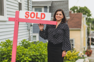 realtor standing by Sold sign in front of house